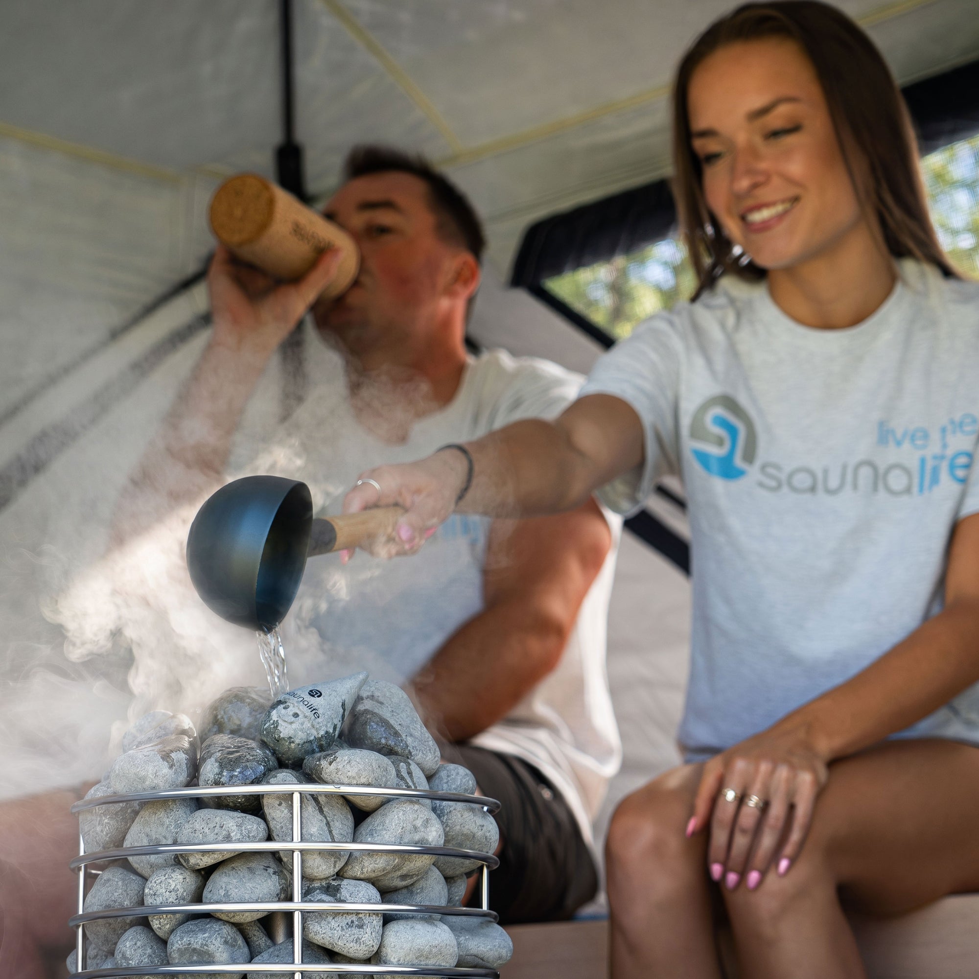 SaunaLife SaunaTrekker XL portable sauna tent interior with users creating steam over sauna stones