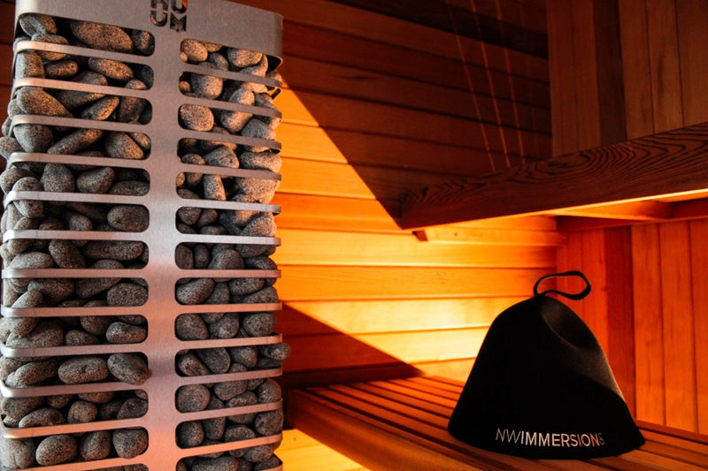 Sauna heater stones with an NW Immersion hat resting on the cedar bench