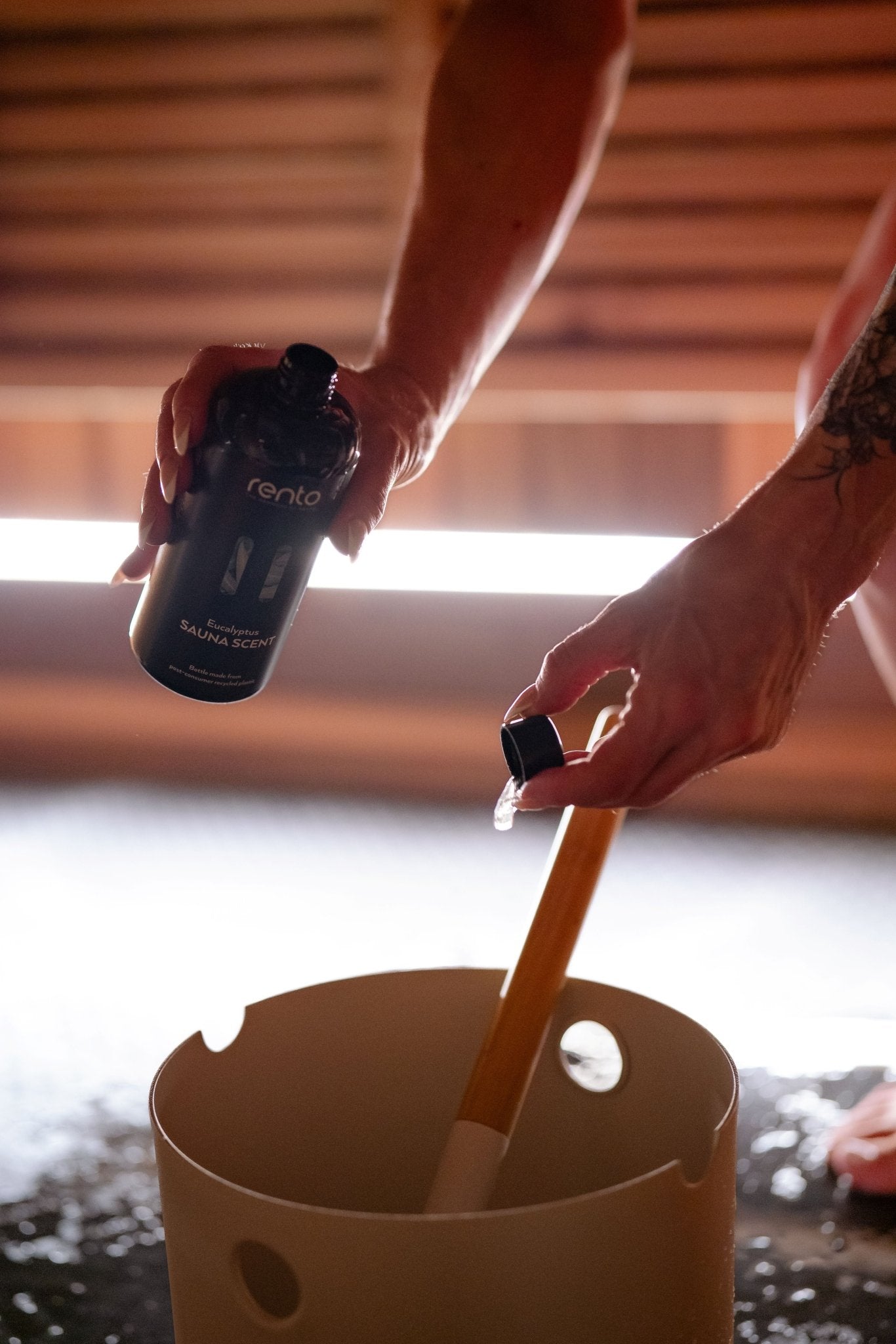 Person pouring Rento Eucalyptus sauna scent into a bucket for Finnish löyly steam.